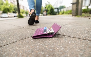 Close-up of a wallet on a sidewalk. The woman who dropped it doesn't know and is walking away.