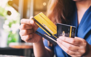Close-up of a woman holding three credit cards fanned out, deciding which card is the best.