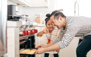 Adorable young asian girl, about 6 years old, baking cookies with her dad