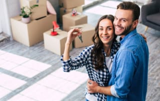A young couple happily holding keys to their new home