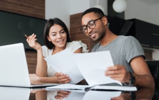 Attractive couple reviews paperwork in front of a laptop