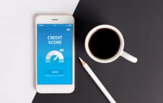 Aerial shot of a mobile phone displaying a credit score, sitting next to a coffee mug and pencil