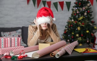 Depressed frustrated woman wrapping Christmas gift boxes, winter holiday stress concept