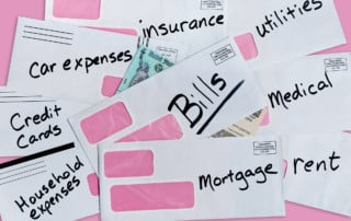 Stimulus check partially buried under multiple bills and envelopes with writing on the outside like bills, mortgage, car expenses, and more