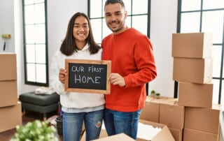 Young latin couple smiling happy holding blackboard with our first home message.